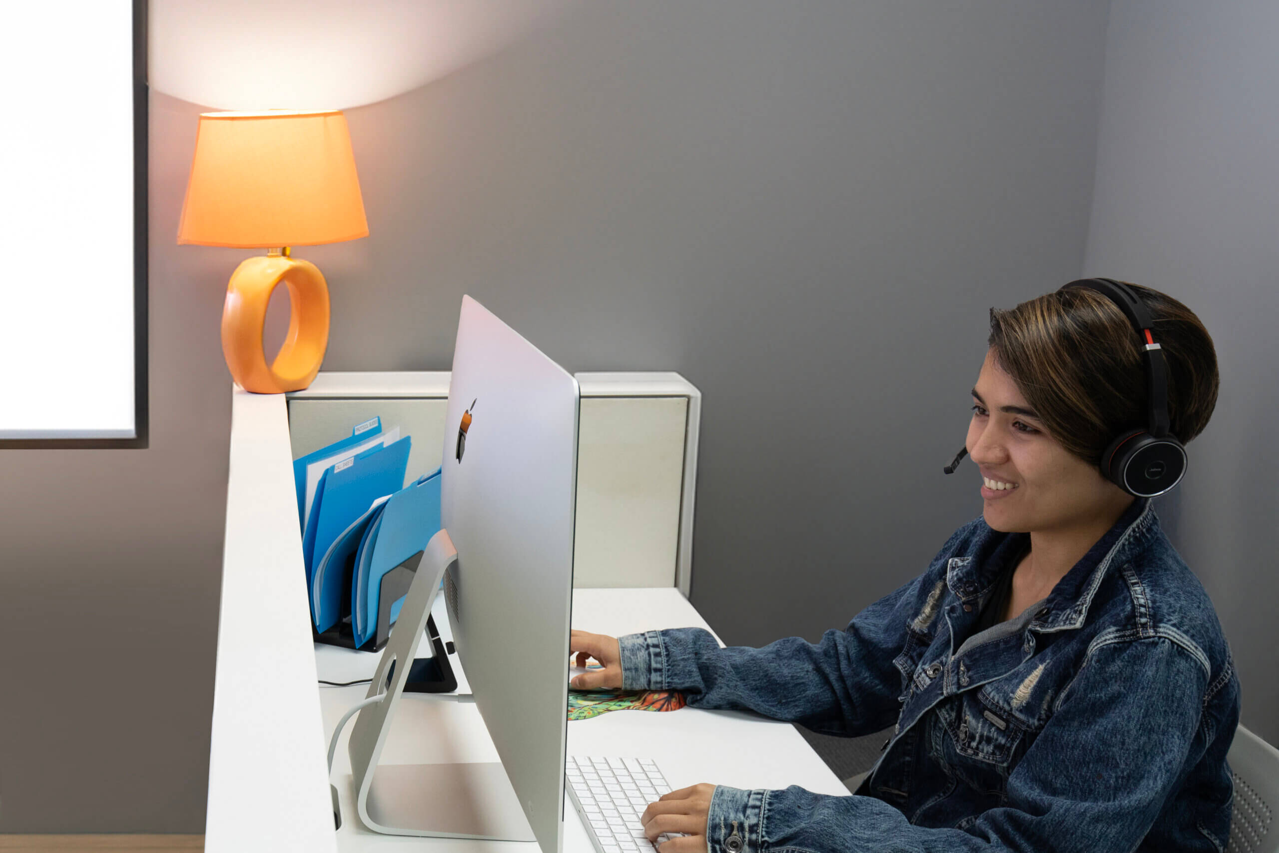 A Trevor employee wearing a headset, sits at a computer and takes a call from an LGBTQ+ young person