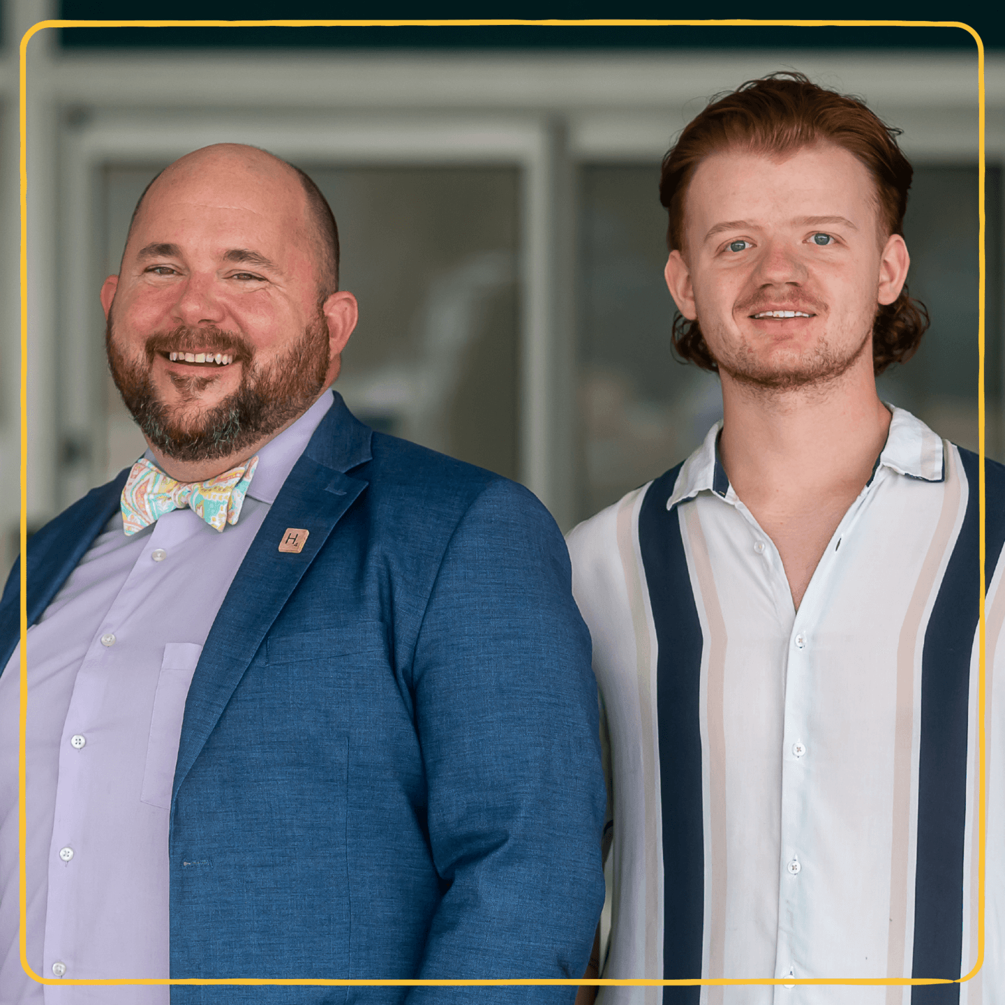A teacher in a blazer and bow tie smiles next to an LGBTQ+ student.