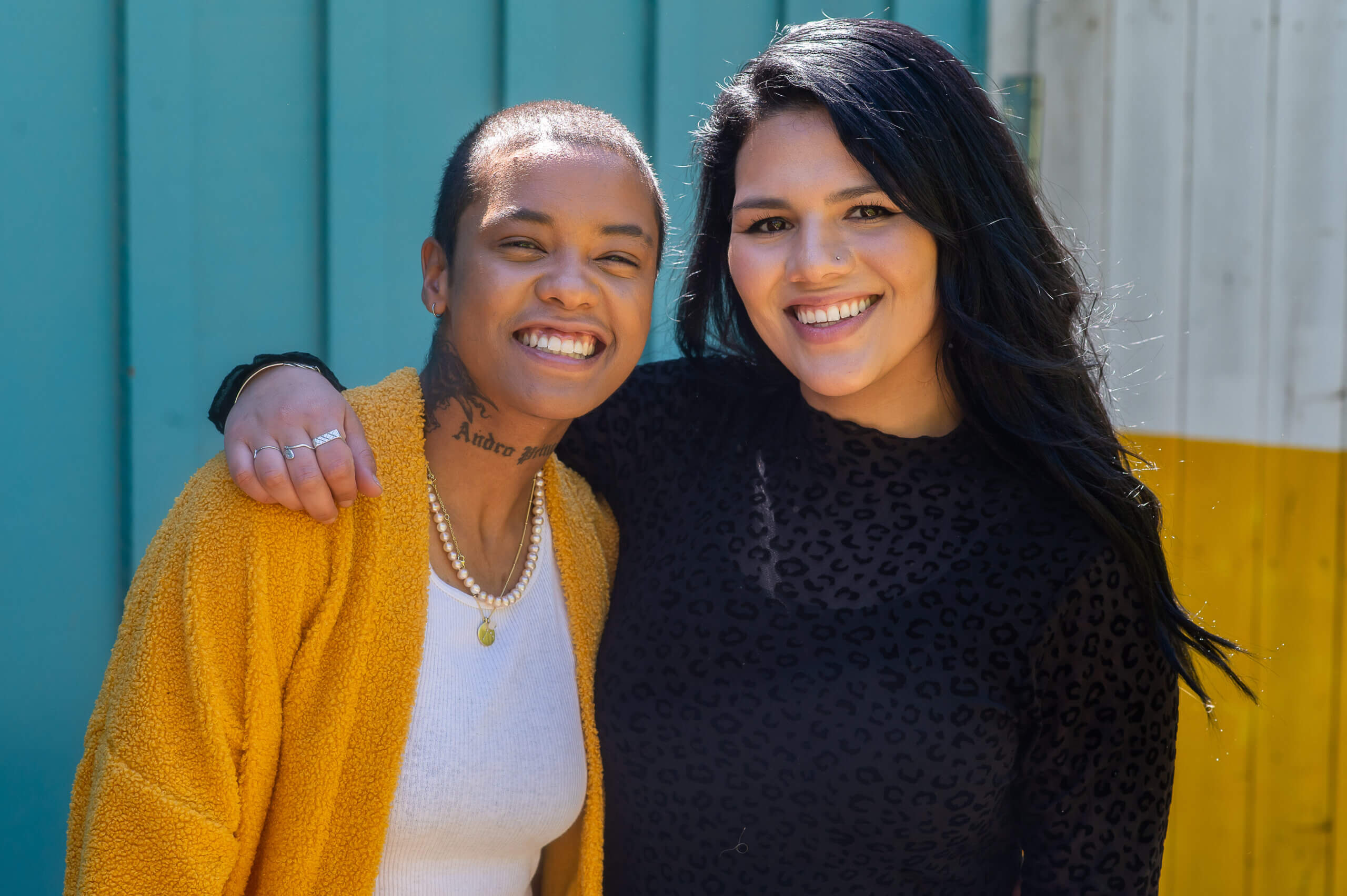 Two LGBTQ+ young people smile at the camera.